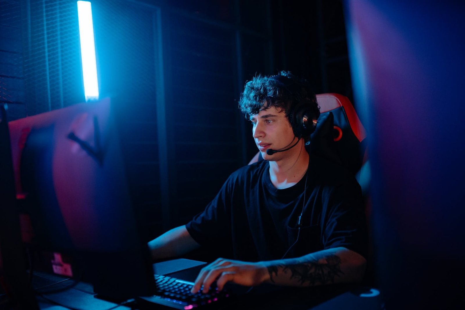 a tattooed man in a black shirt gaming on a desktop