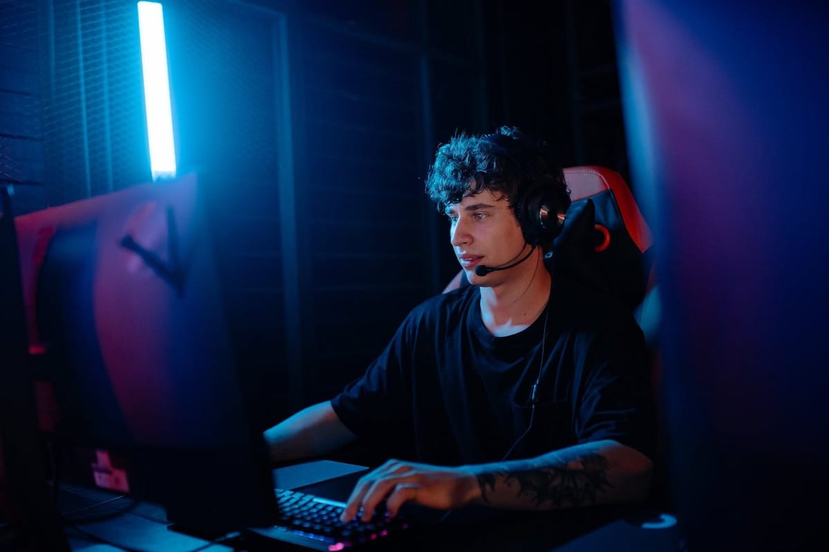 a tattooed man in a black shirt gaming on a desktop